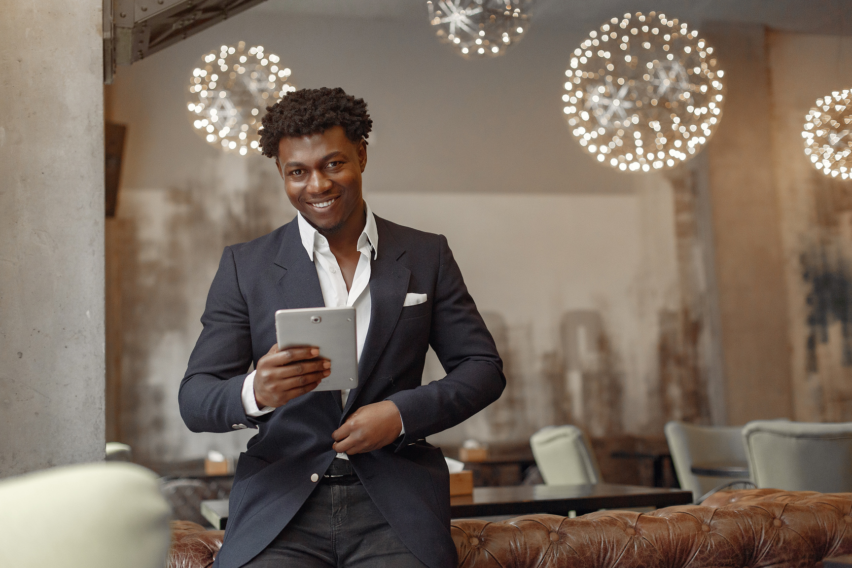 Cheerful businessman with tablet in restaurant